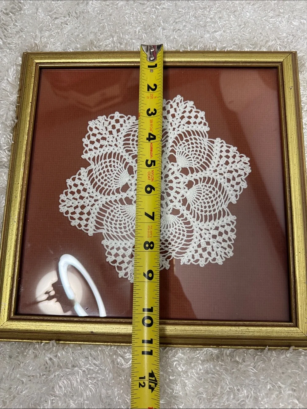 Framed doily in gold frame